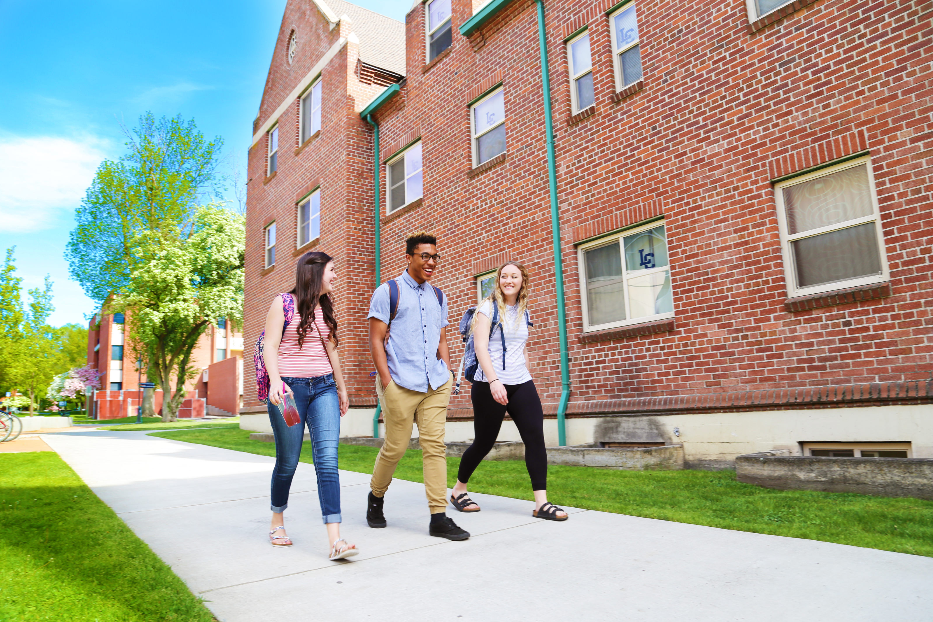 A group of three students walking outside in front of Talkington Hall