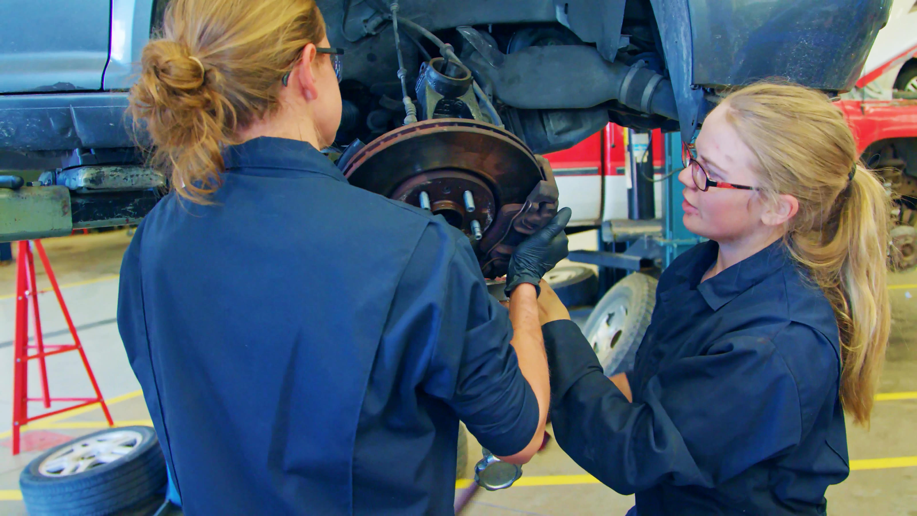 Two female students working on a tire of a car