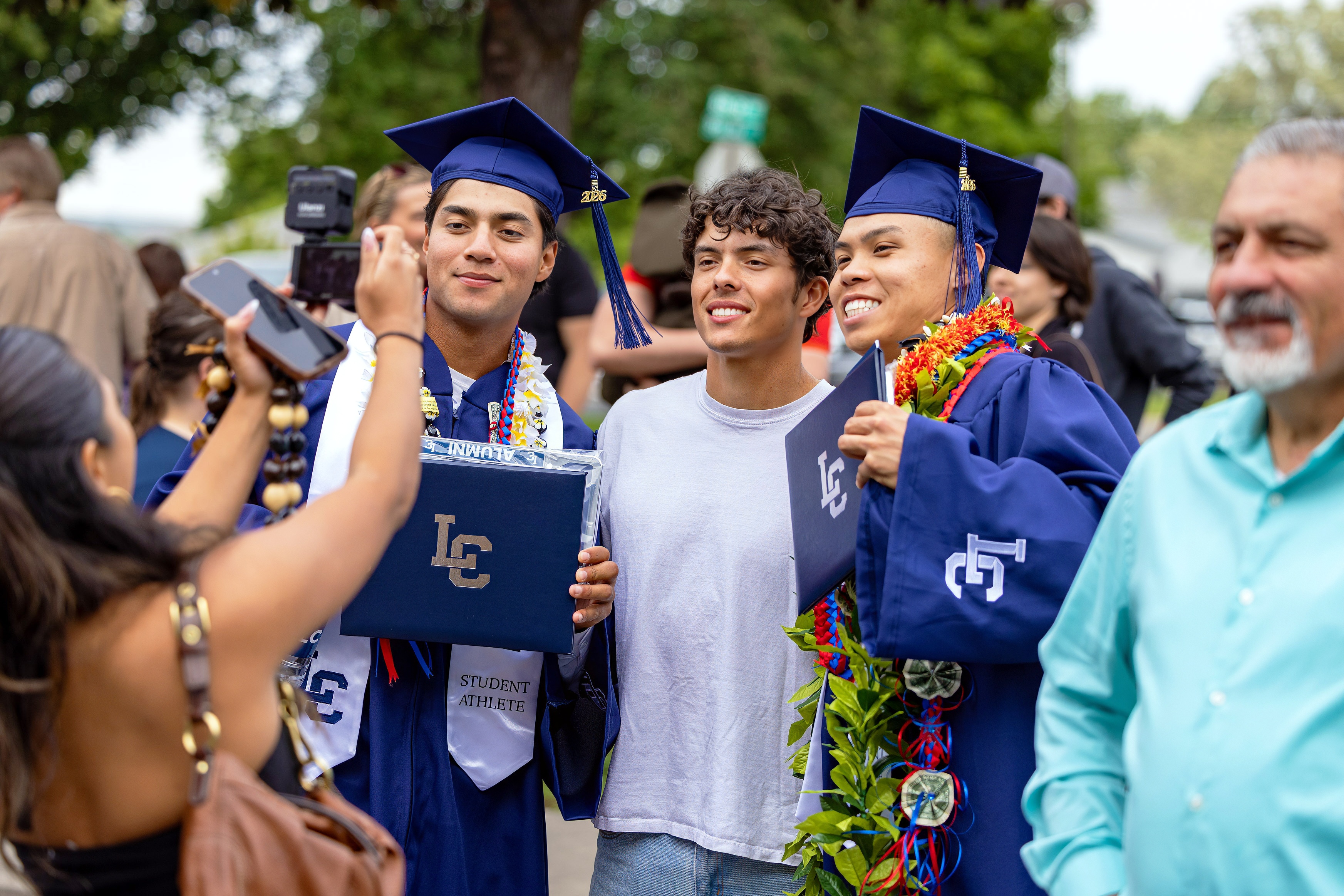 Two graduates alongside a friend at commencement