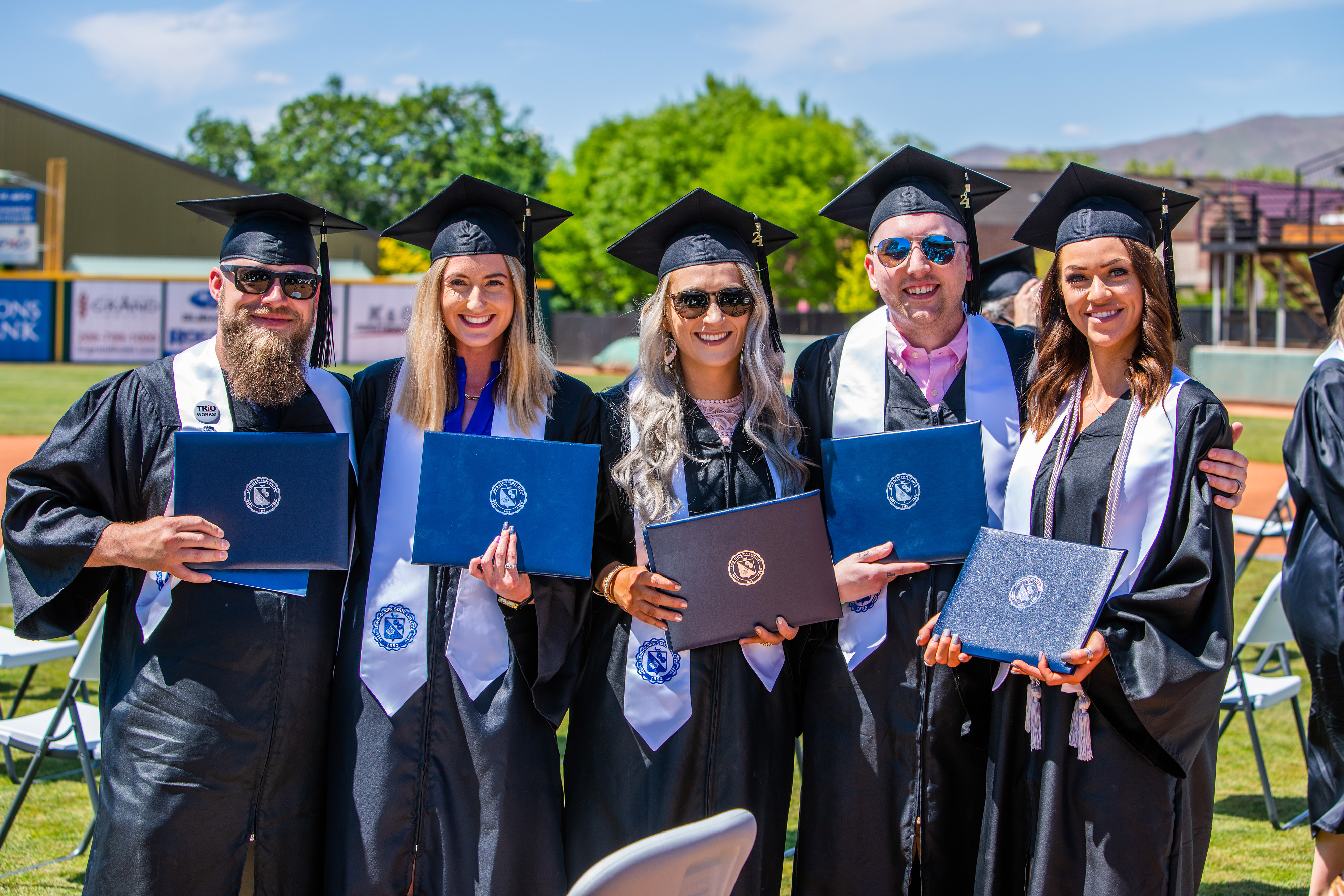 Five students at outdoor graduation ceremony