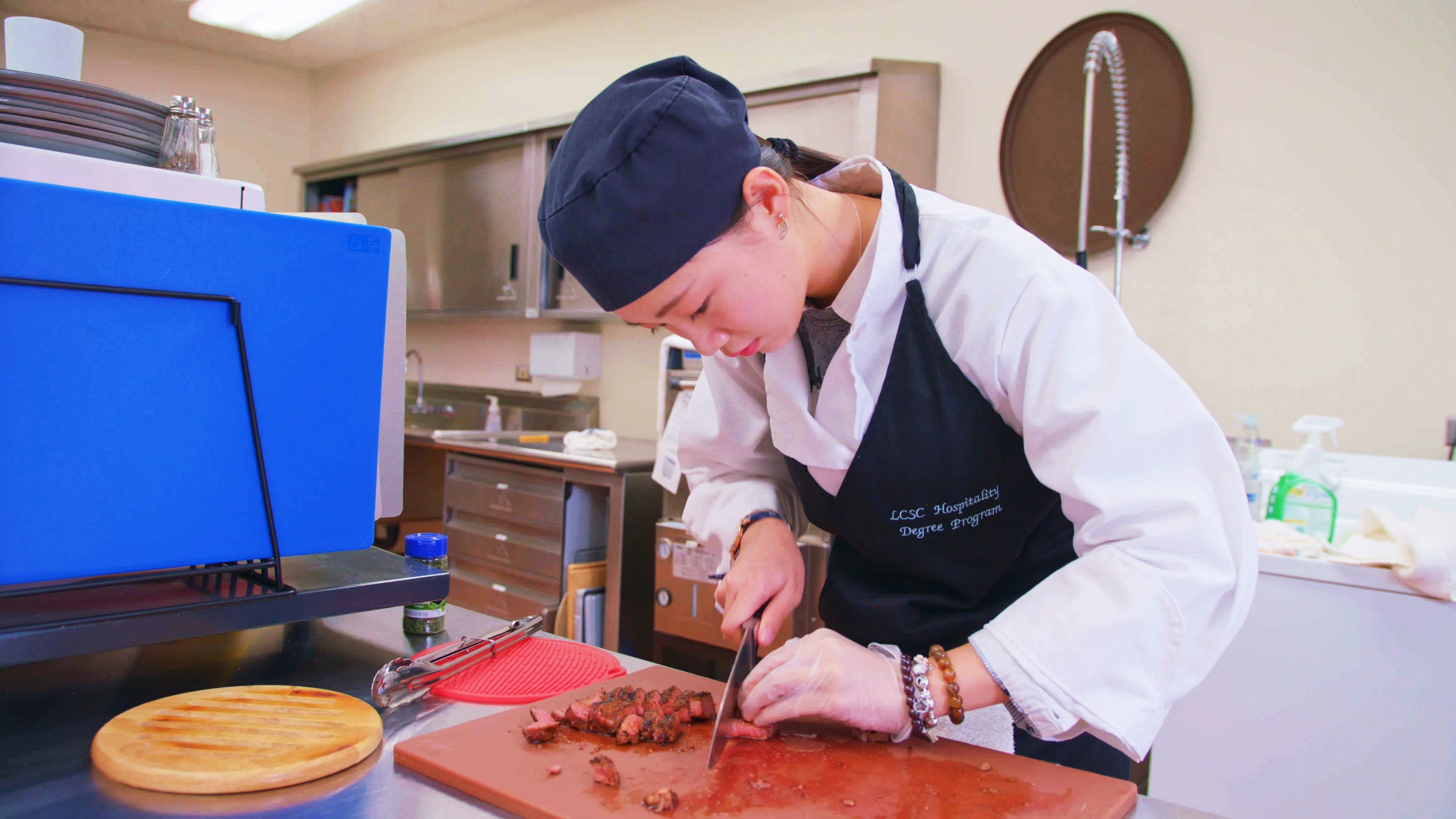 Hospitality Management program student cutting meat
