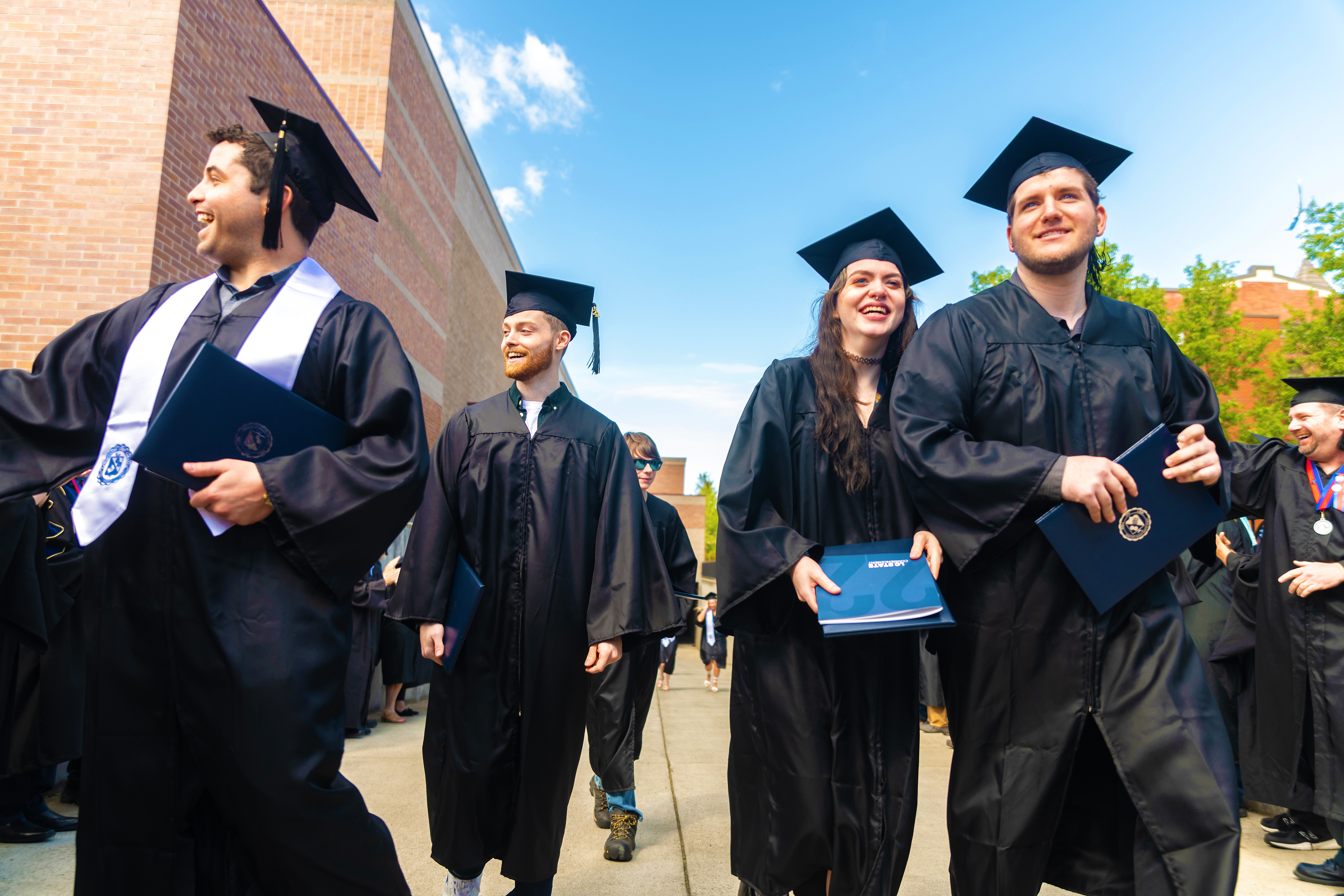 Four graduates smiling at commencement 