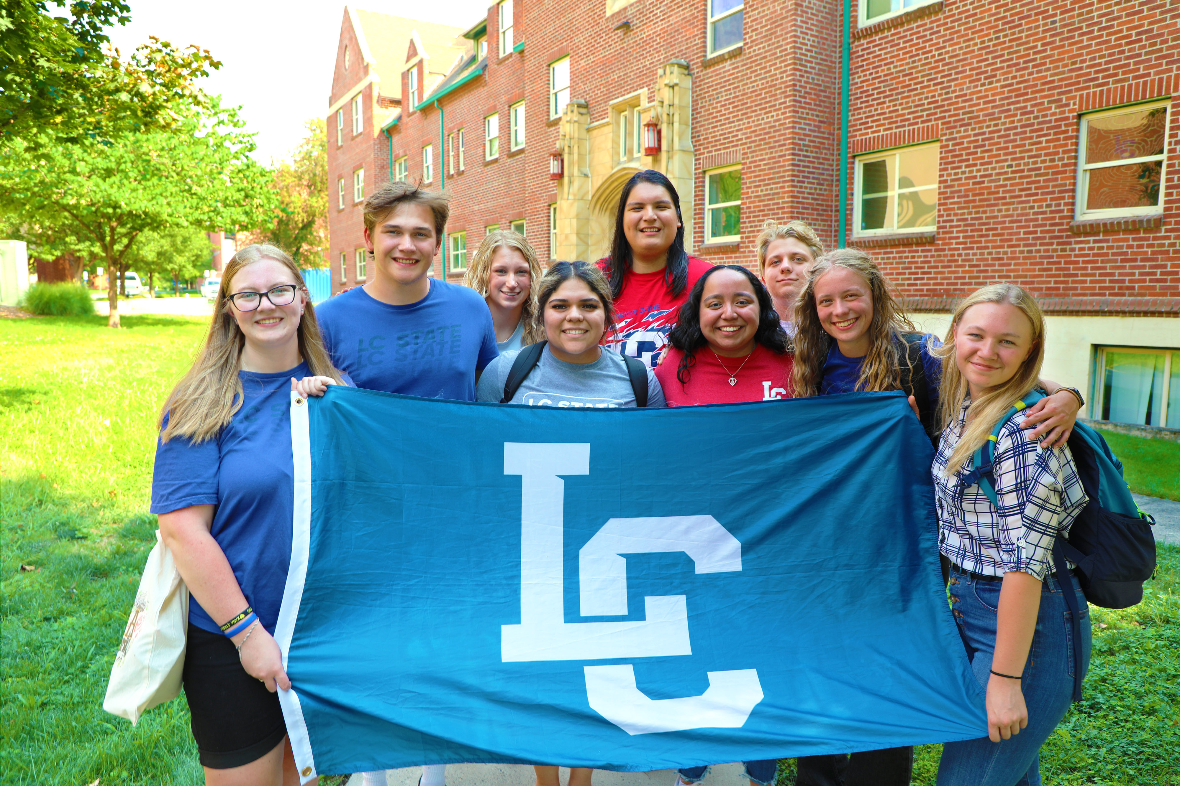 LC State Students posed in group holding LC State Flag on campus 