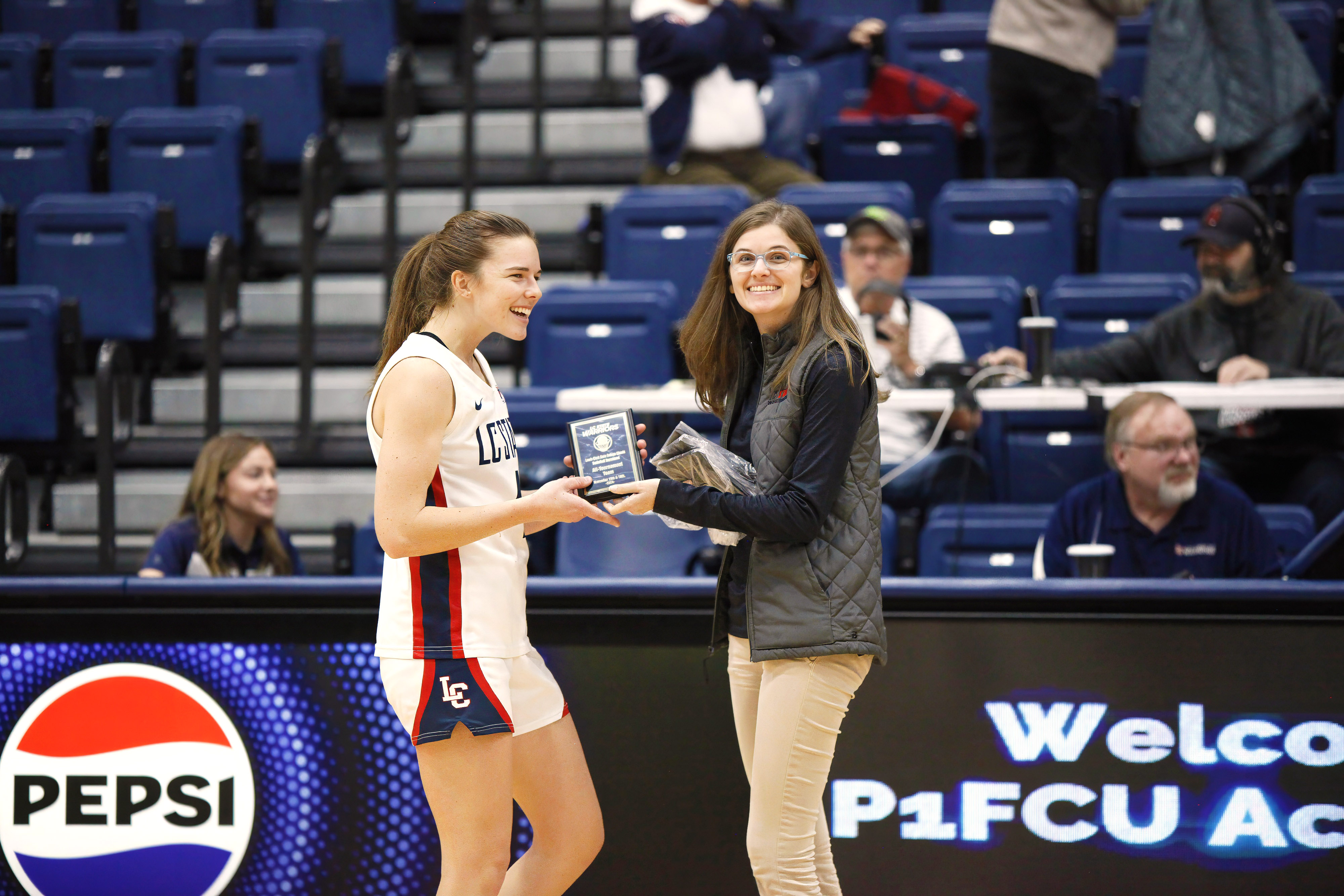 Alisha Alexander handing award to LC State athlete in P1FCU Activity Center 